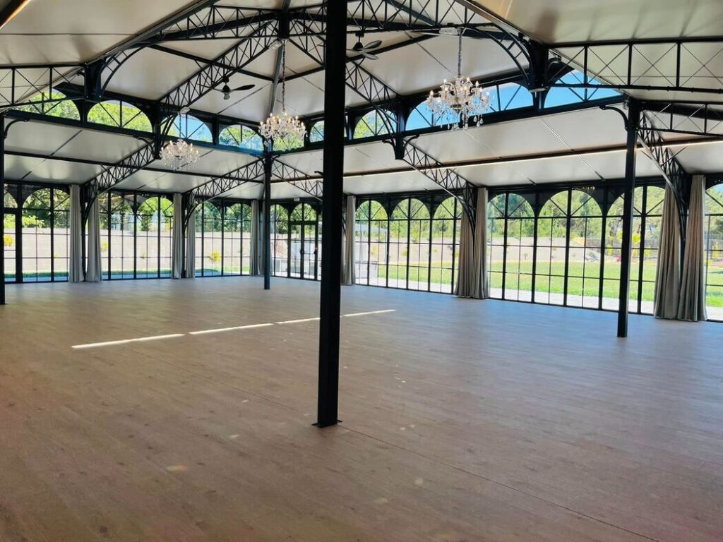 Salle de réception vide avec structure métallique et baies vitrées aux Arches de la Ria