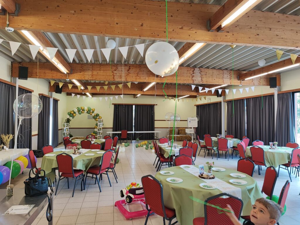 Salle de réception avec tables à nappes vertes, fanions et ballons