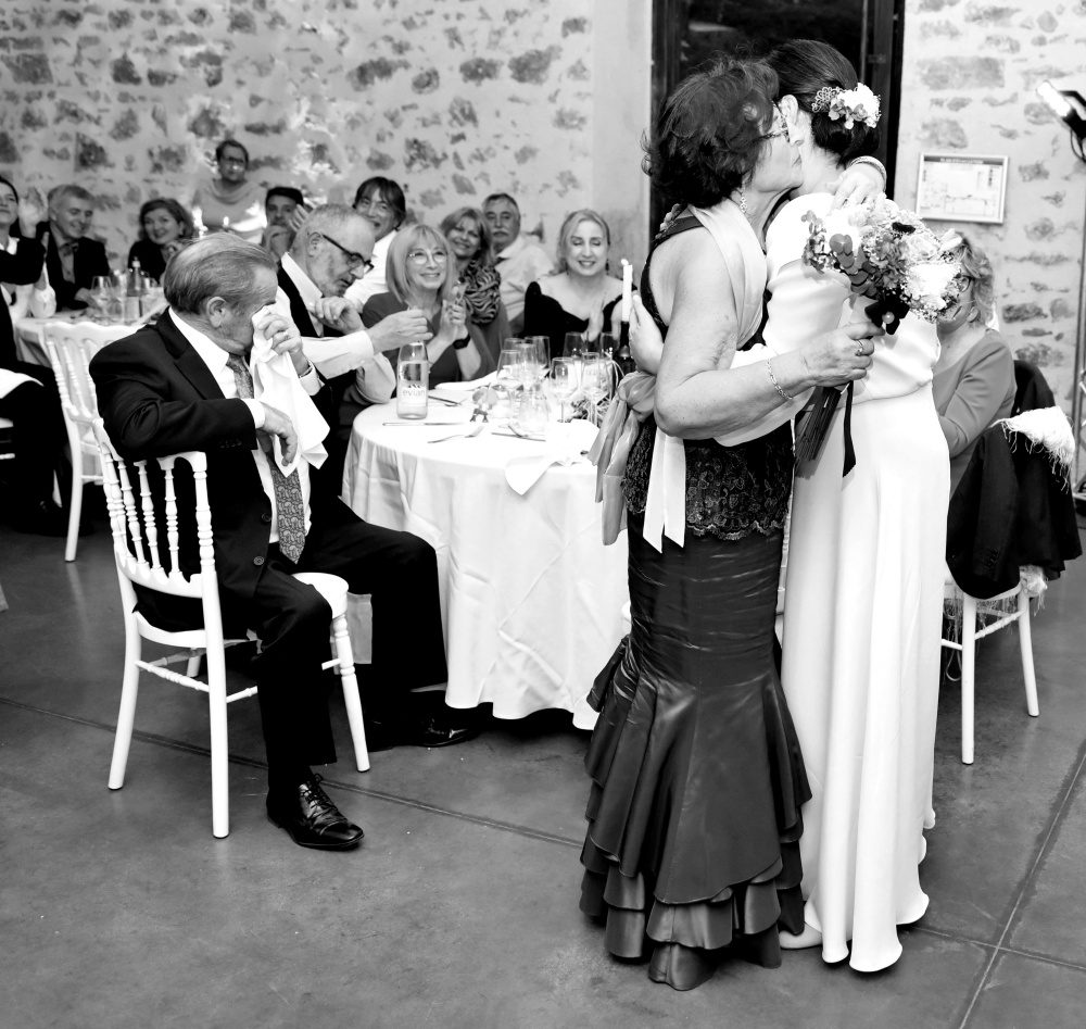 Mariée embrassant une invitée pendant le repas, en noir et blanc — MB Photografik