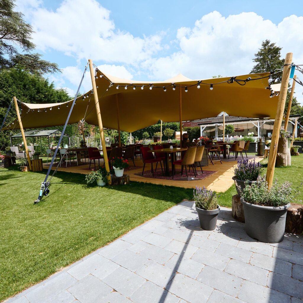 Tente stretch et tables installées dans un jardin par Fête24