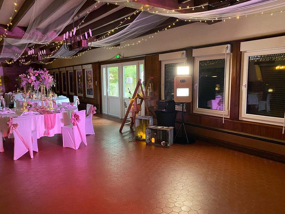 Photobooth en bois installé dans une salle de réception décorée en rose