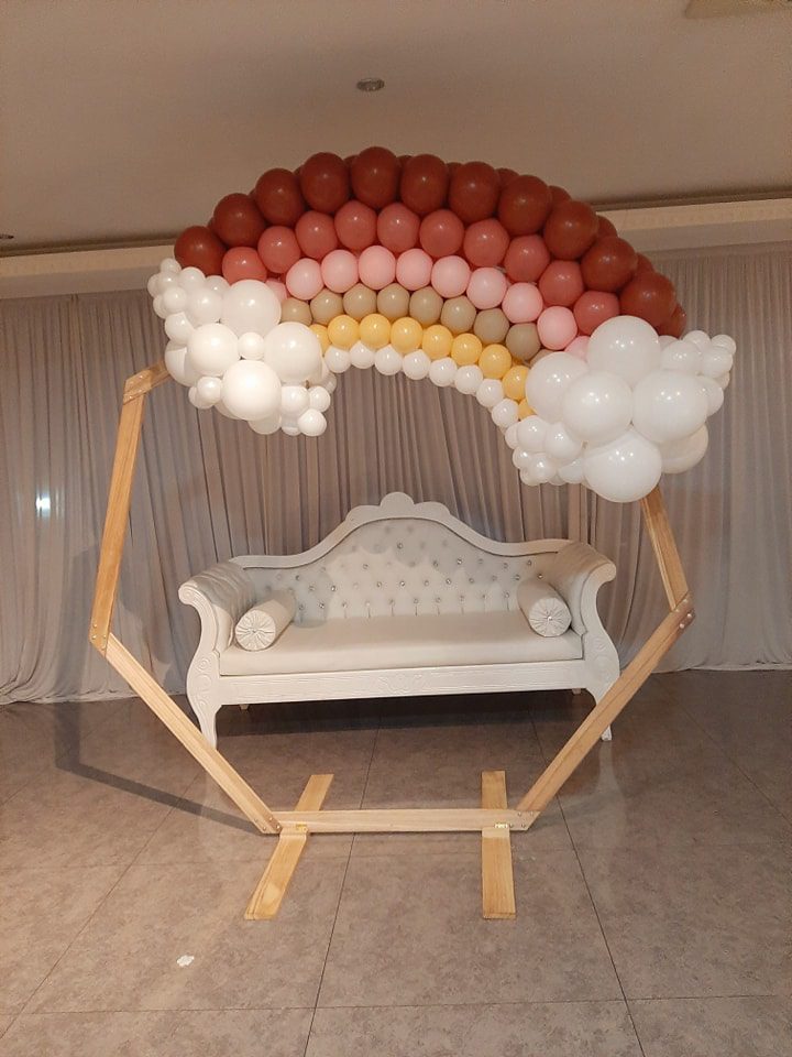 Arche en bois avec ballons en arc-en-ciel et canapé blanc – Elodie Events