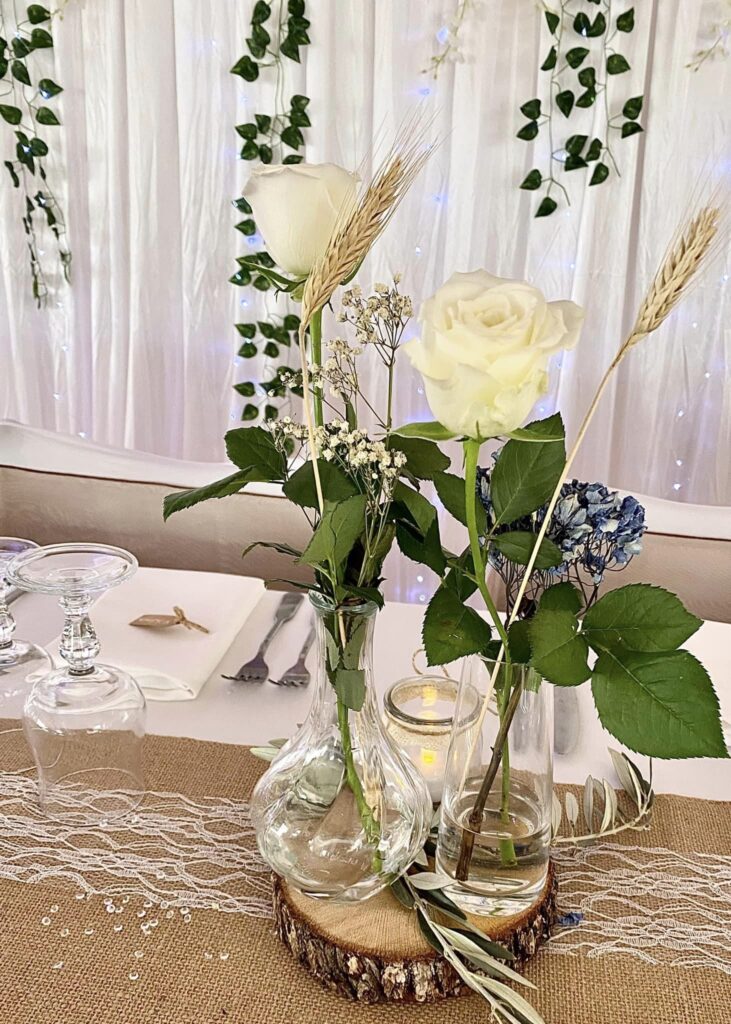 Roses et petites compositions florales sur une table de réception