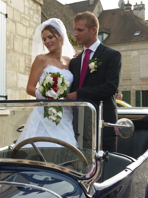 Couple de mariés debout dans une voiture ancienne décapotable