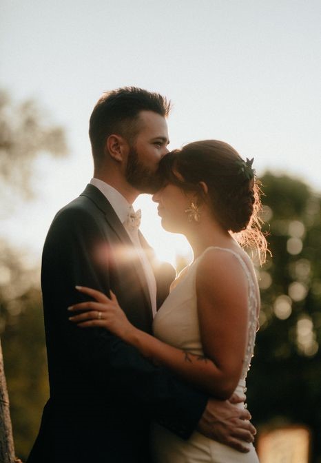 Marié embrassant le front de la mariée en contre-jour