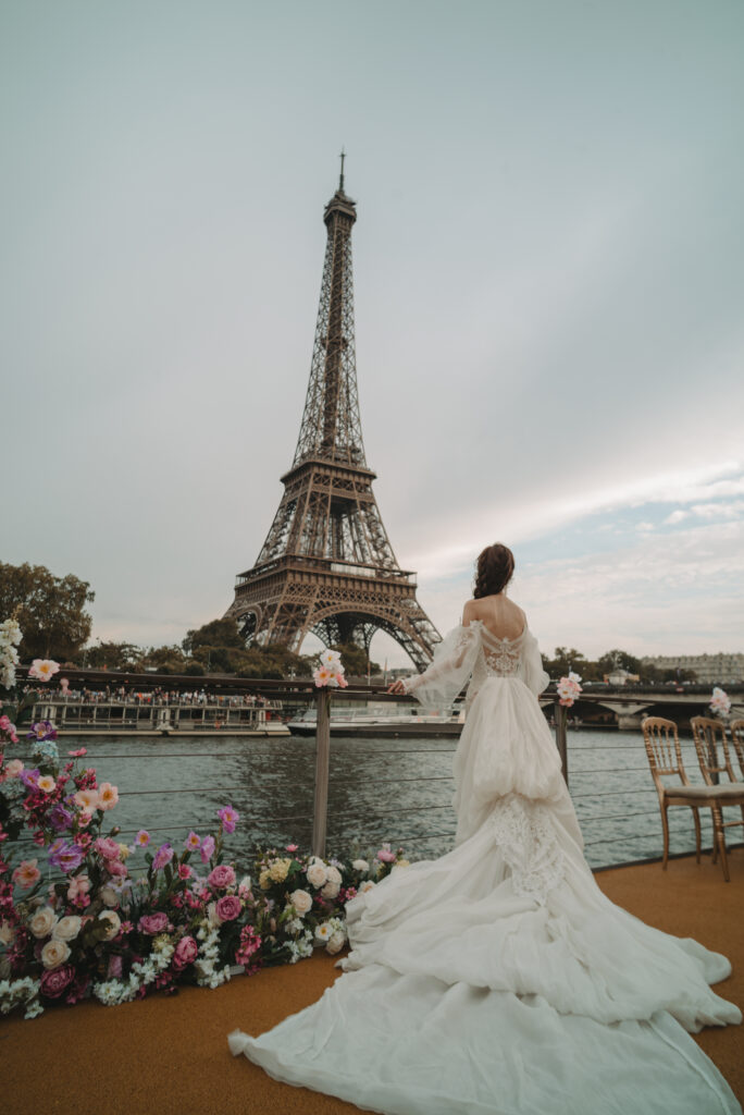 Mariée devant la tour Eiffel, au bord de la Seine, avec un décor floral rose et blanc — galerie Rock and flowers