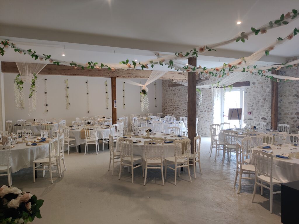 Salle de réception avec tables rondes, chaises blanches et décoration végétale