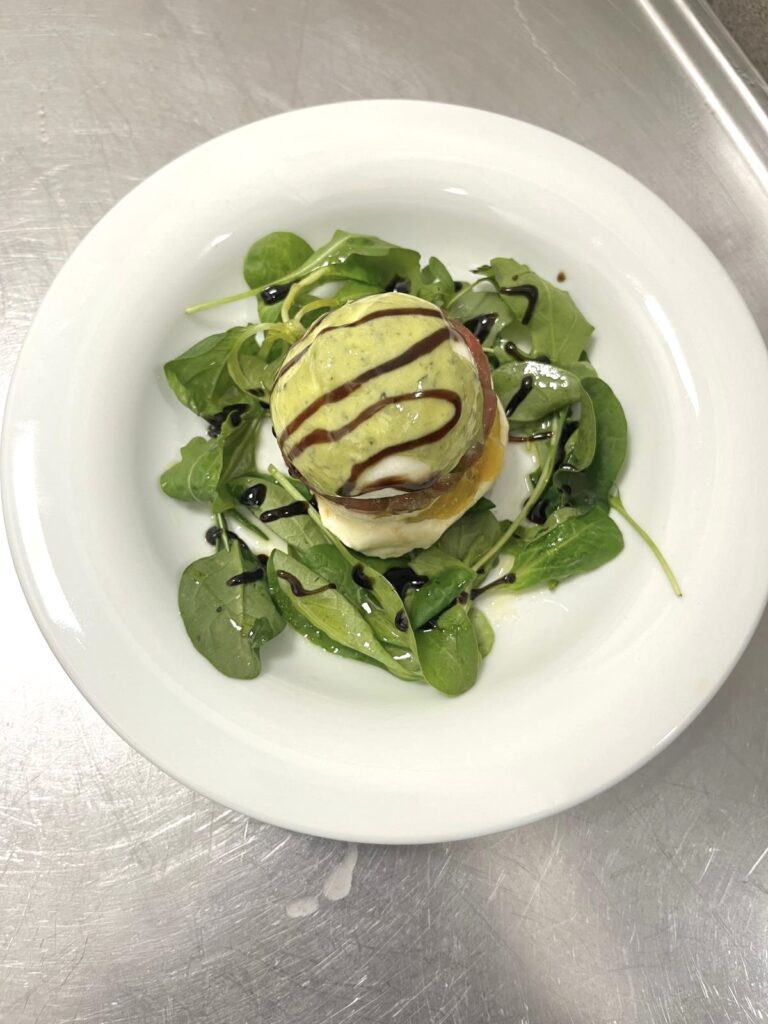 Assiette dressée sur un lit de salade avec sauces verte et sombre