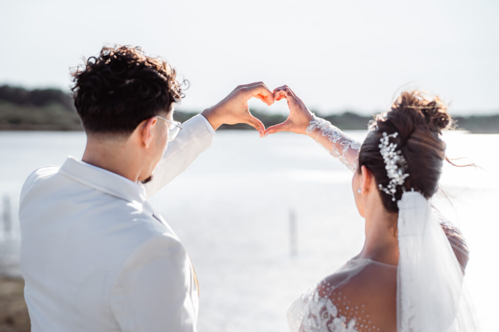 Mariés formant un cœur avec leurs mains au bord de l’eau — Jim Mariage