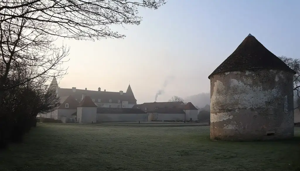 Stone tower with Château de Chailly-sur-Armançon in the background, viewed from the park, March 2023.