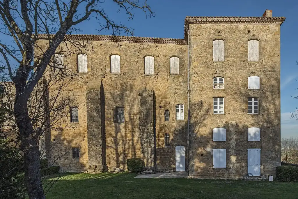 Façade sud-ouest en pierre et volets clairs du château de Saint-Félix-Lauragais, devant la pelouse
