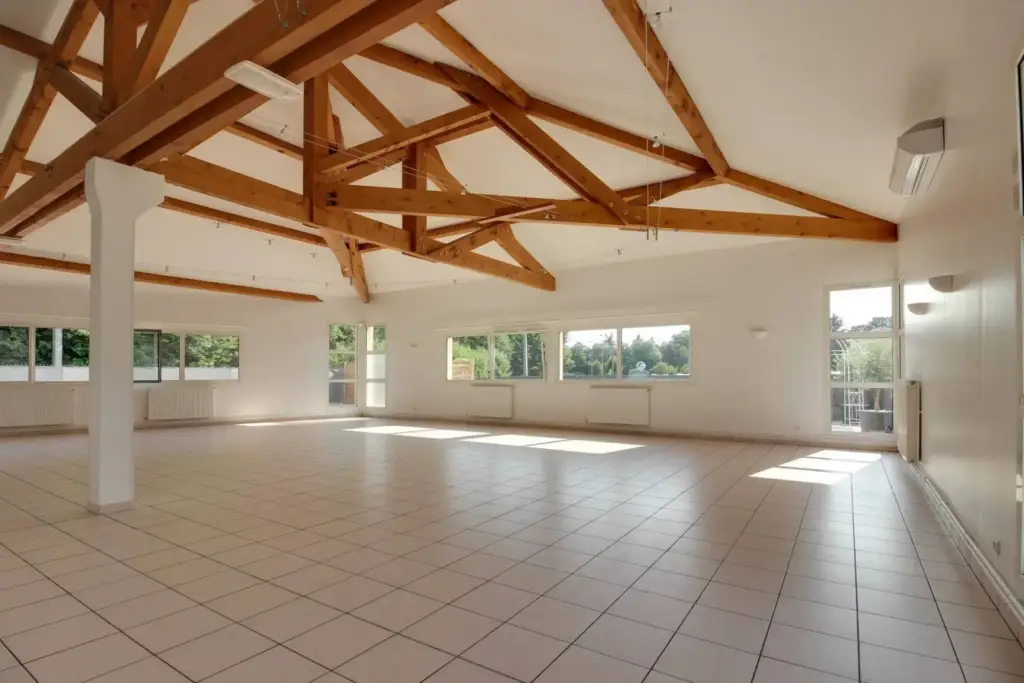 Salle lumineuse du Domaine du Ruisseau à Thurins avec charpente apparente