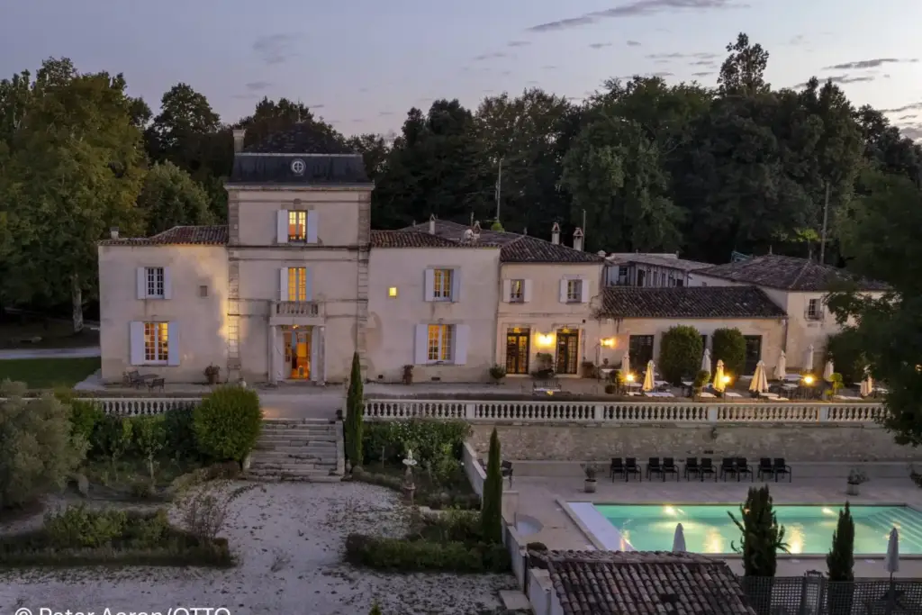 Façade of Château de Lantic in Martillac, with the terrace and illuminated swimming pool