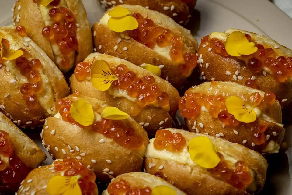 Bouchées cocktail garnies de perles orangées et de fleurs jaunes, présentées par Riv’K Traiteur