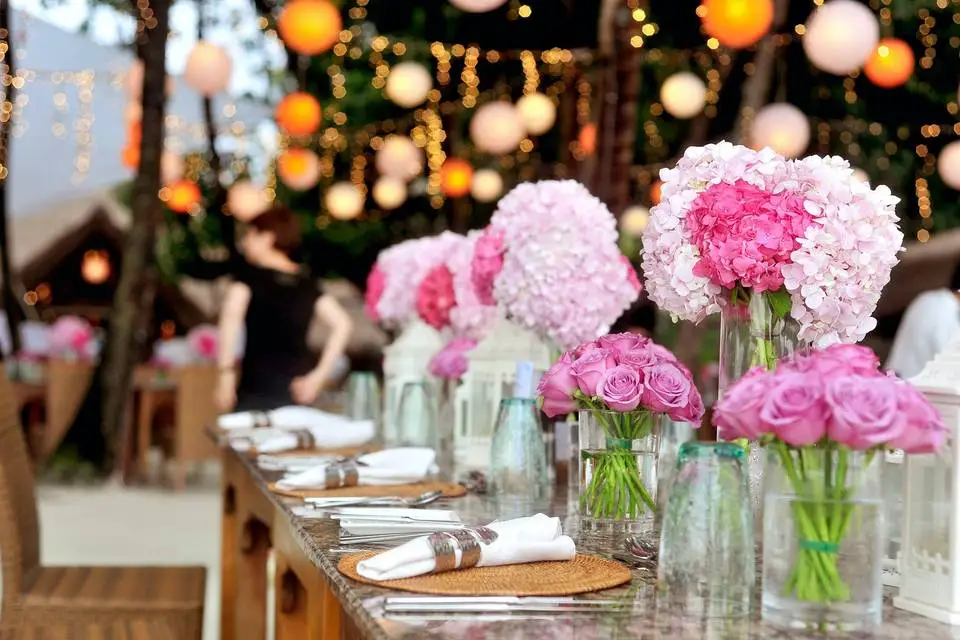 Table de réception ornée de bouquets roses et de lumières, présentée dans la galerie de HBK Traiteur