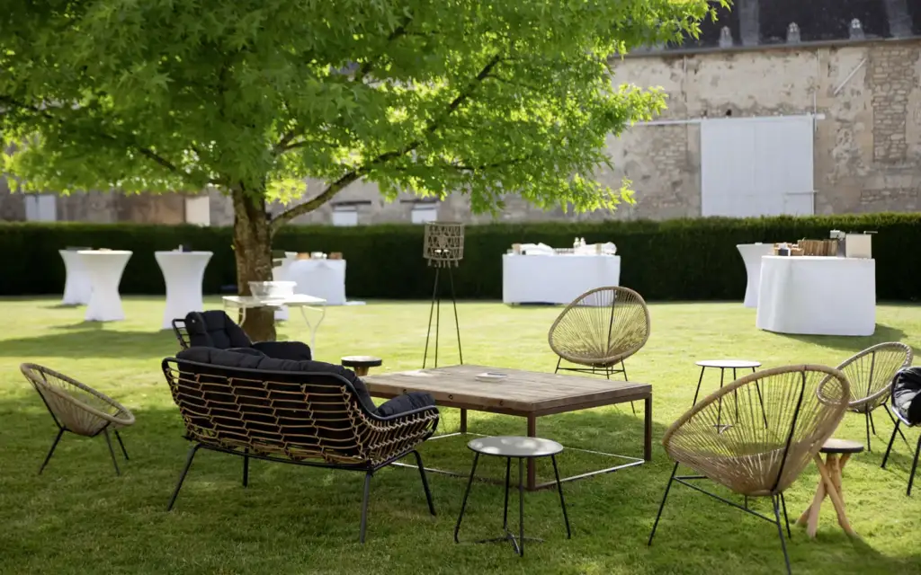 Jardin de La Ferme des Tournelles aménagé avec tables de cocktail et sièges