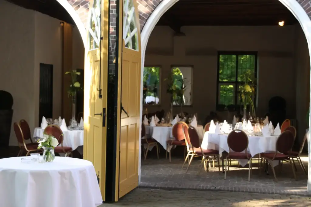 Gedekte ronde dinertafels bij de open deuren van de Koetshuizen van Kasteel Heeze