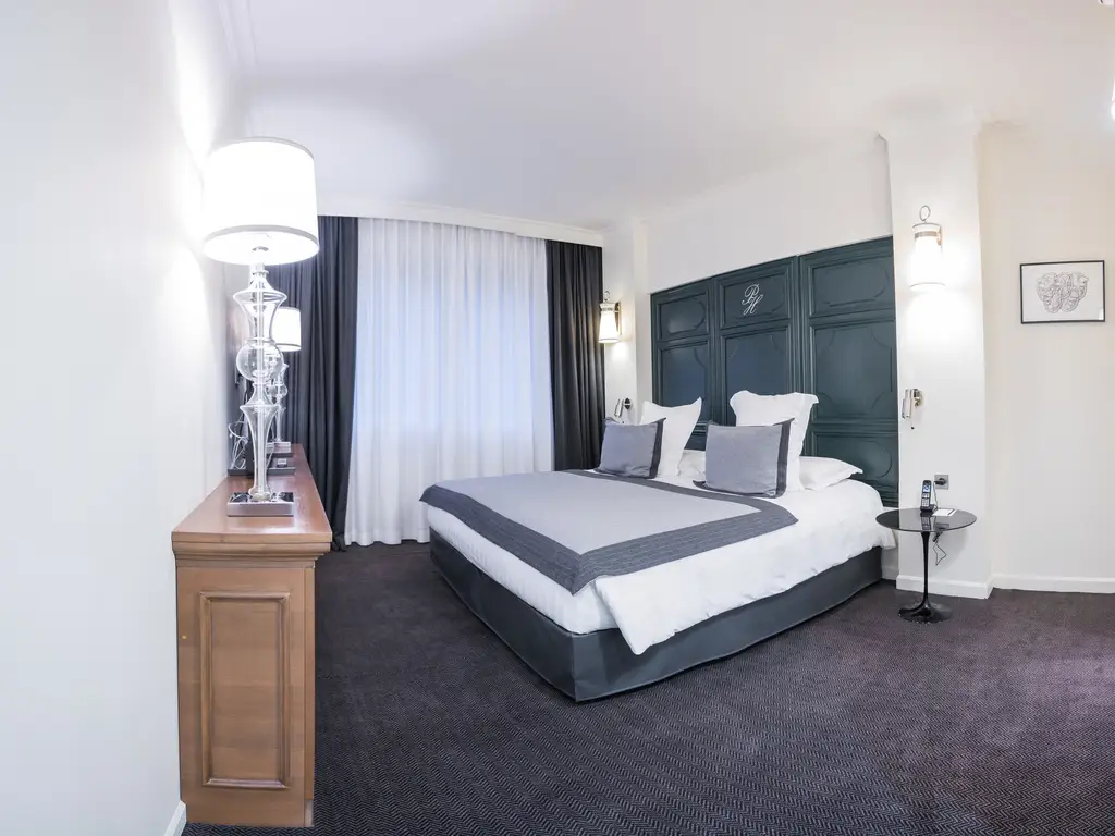 Chambre de suite au Park Hôtel Grenoble avec grand lit et tête de lit à panneaux verts