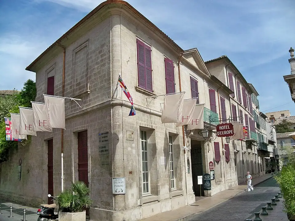 Façade en pierre de l’Hôtel d’Europe à Avignon, avec volets bordeaux et enseigne au-dessus de l’entrée