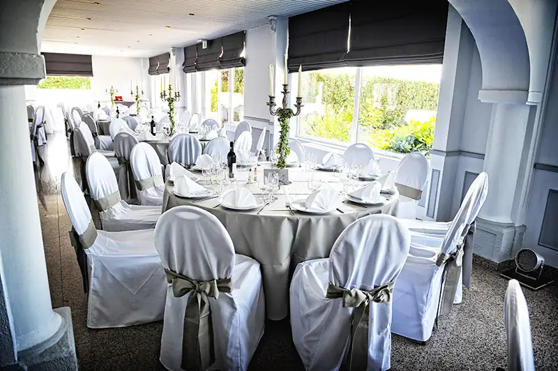 Tables de réception dressées dans une salle lumineuse du Petit Versailles à Gosselies