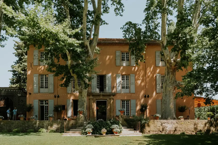 Façade principale de la Bastide de Puget à Meyreuil, entourée de grands platanes et d'une pelouse