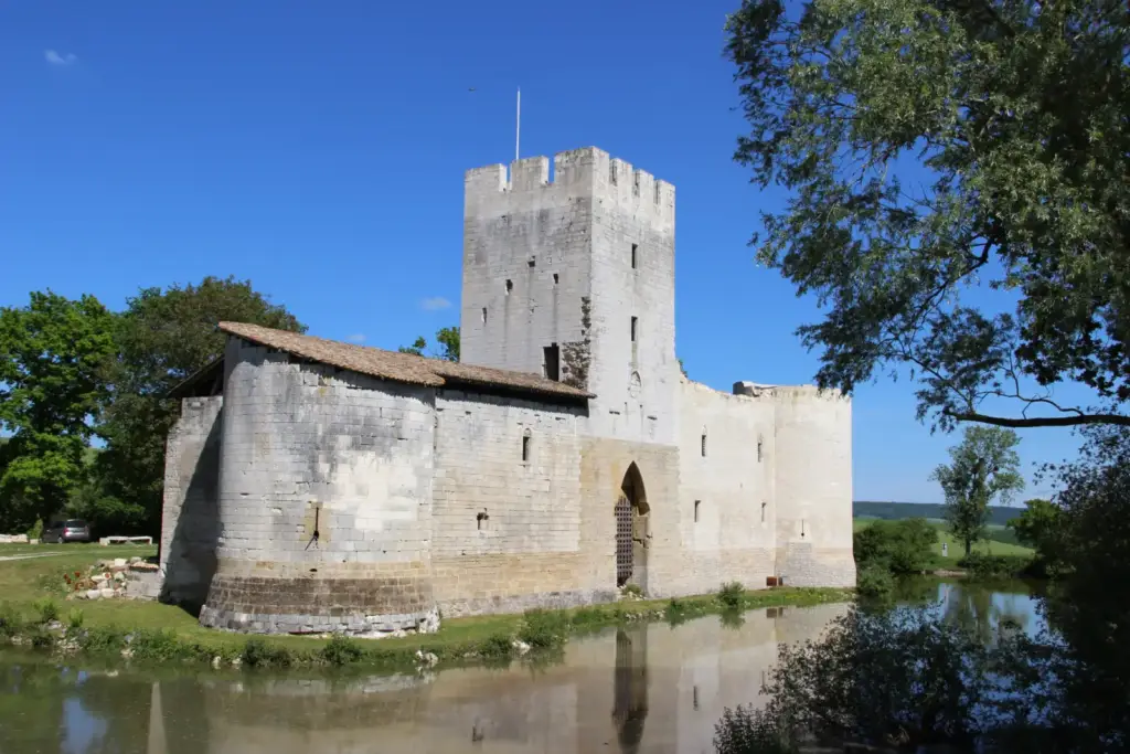 Château de Gombervaux et donjon carré reflétés dans les douves, vus sous les arbres