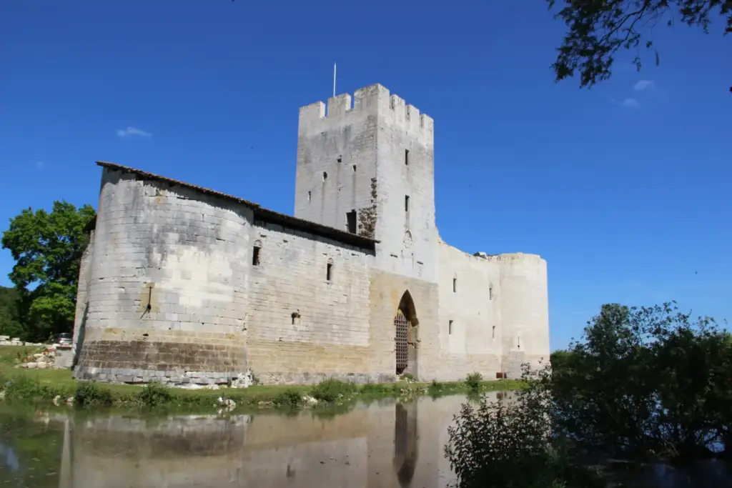 Façade de pierre et tours de Gombervaux au bord des douves, sous un ciel bleu