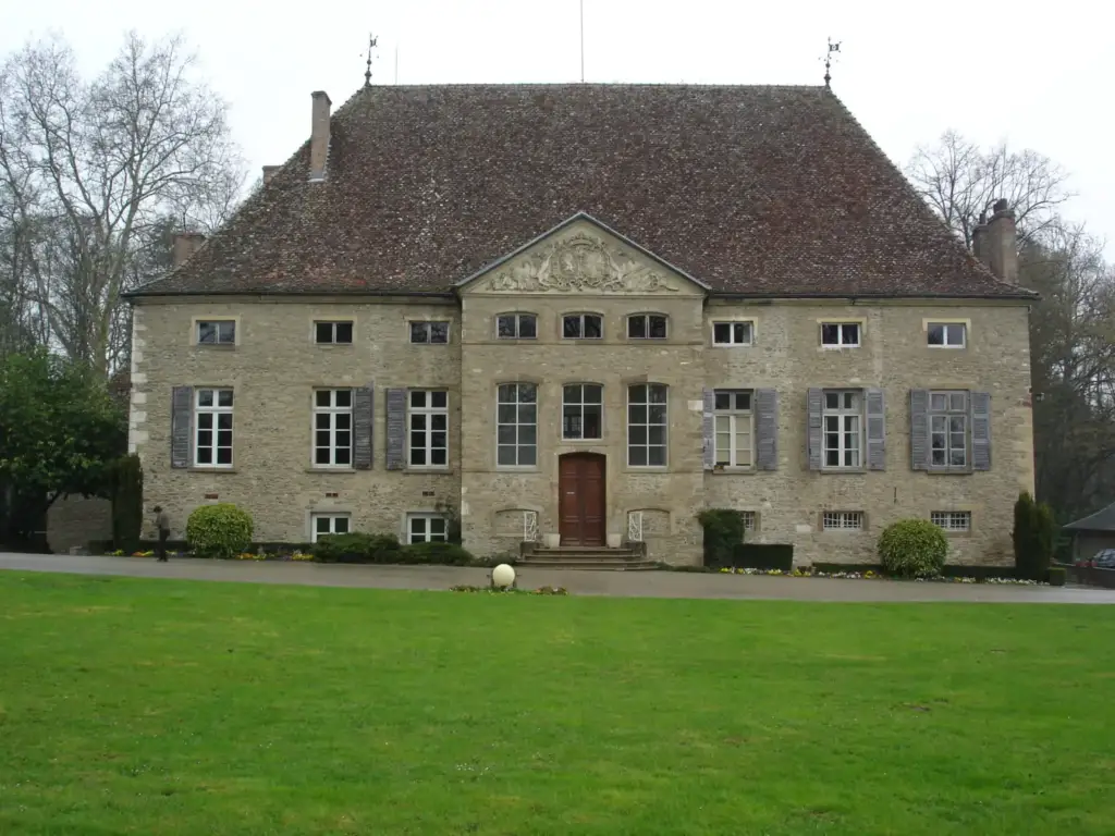 Façade en pierre du château de Dolomieu, fronton sculpté et pelouse au premier plan