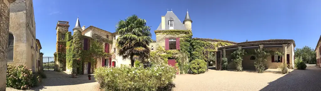 Cour arborée et bâtiments en pierre du Château Sentout à Tabanac