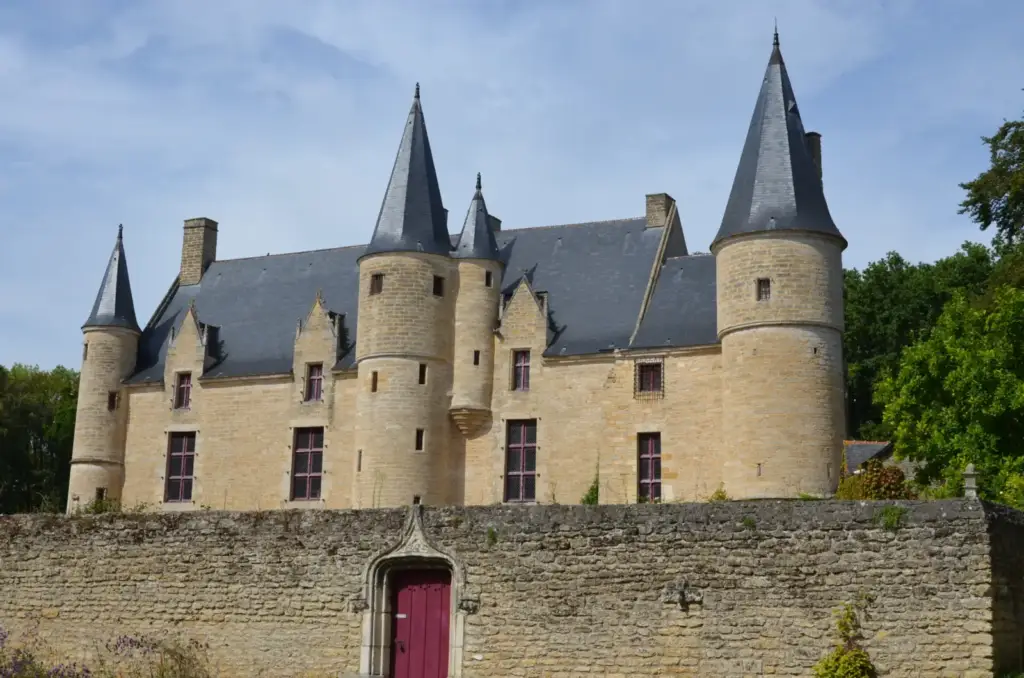 Château de Hac et ses tourelles derrière le mur d’enceinte à porte rouge