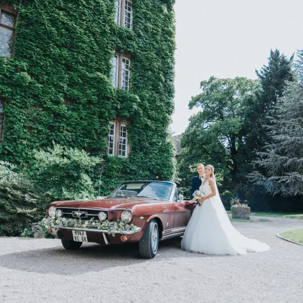 Mariés et voiture ancienne devant la façade végétalisée du Château de la Confrérie Saint-Étienne