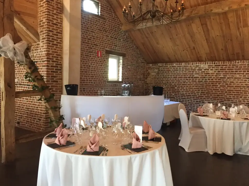 Tables rondes dressées dans la salle de réception de la Ferme du Château d’Oudoumont