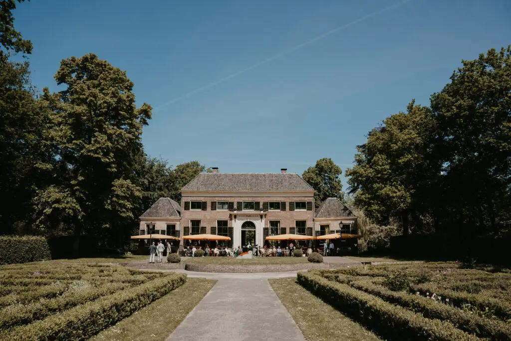 Historische gevel en terras van Dudok In Het Park met de tuin van Het Park