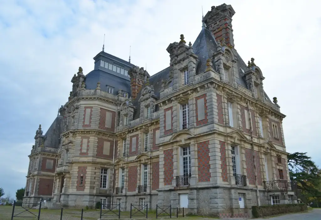 Vue oblique du château de la Turmelière avec tour polygonale, hautes cheminées et façades en brique