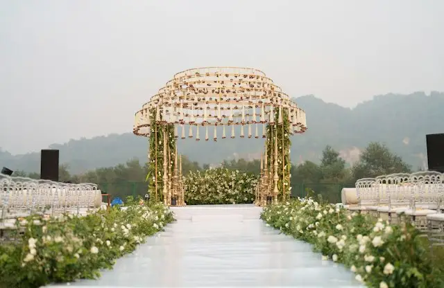 Espace de cérémonie en plein air avec une structure dorée et des fleurs blanches