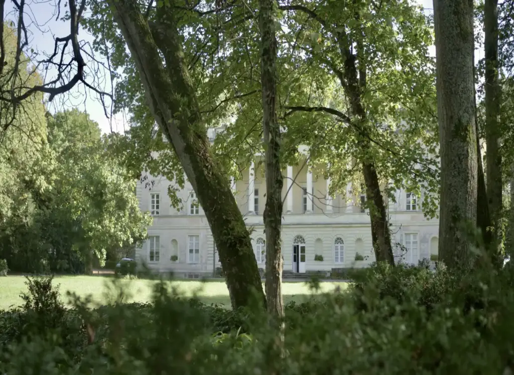 White columned façade of Château de la Noë Bel-Air, seen through the park’s trees in Vallet