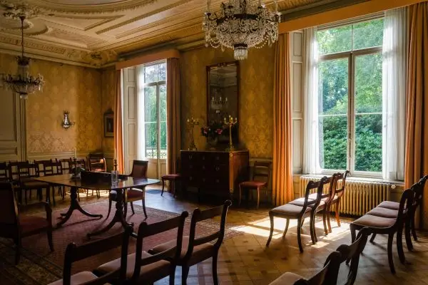 Historisch interieur van de Trouwzaal in Kasteel Geldrop met grote ramen en houten stoelen