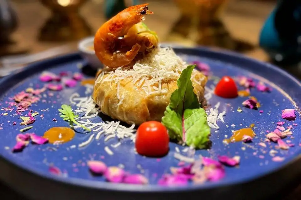 Pastilla surmontée d’une crevette et dressée sur une assiette bleue, présentée par HBK Traiteur