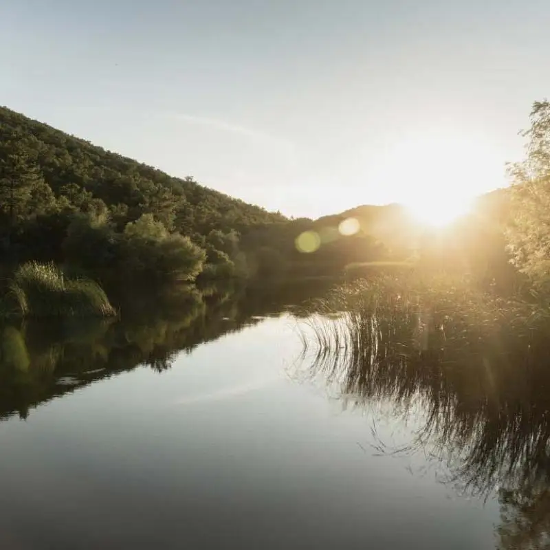 Lac du Château Pas du Cerf au soleil couchant, entouré de collines boisées