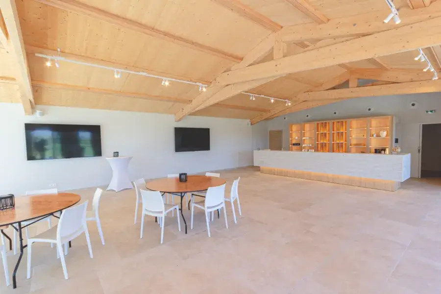 Espace intérieur du Domaine La Baratonne avec poutres apparentes, bar et mobilier de réception