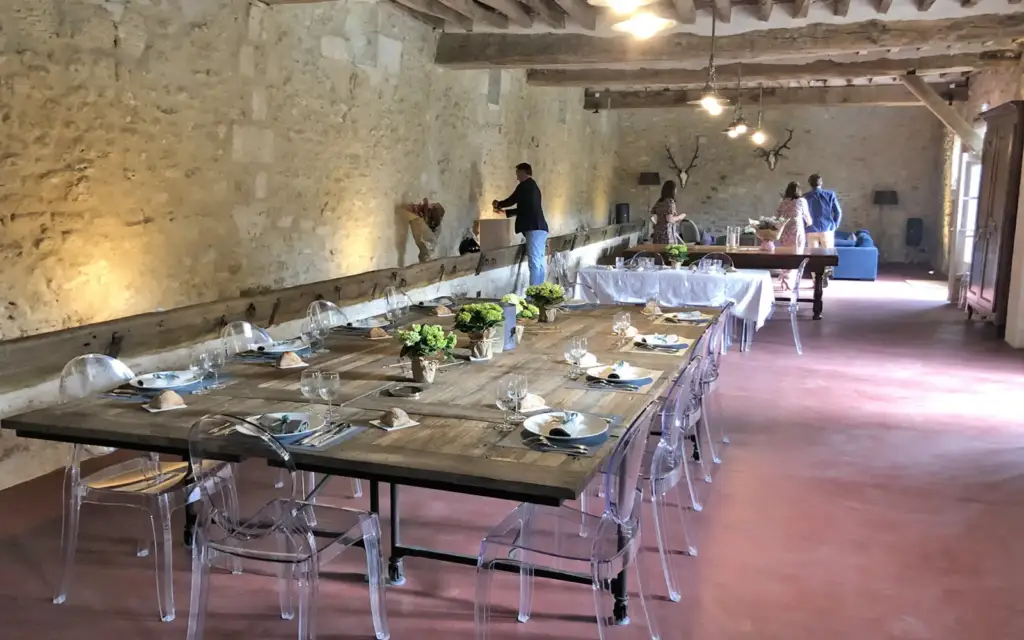 Salle de réception de La Ferme des Tournelles avec poutres apparentes et tables dressées