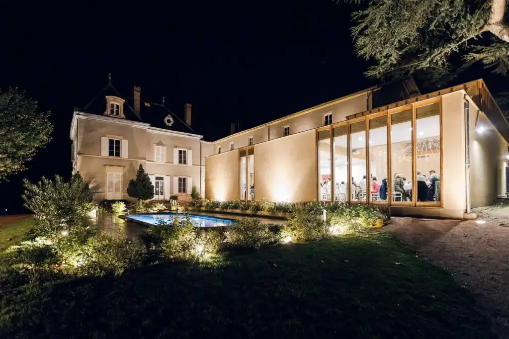 Château des Vierres, façade et verrière de réception illuminées de nuit à Lantignié