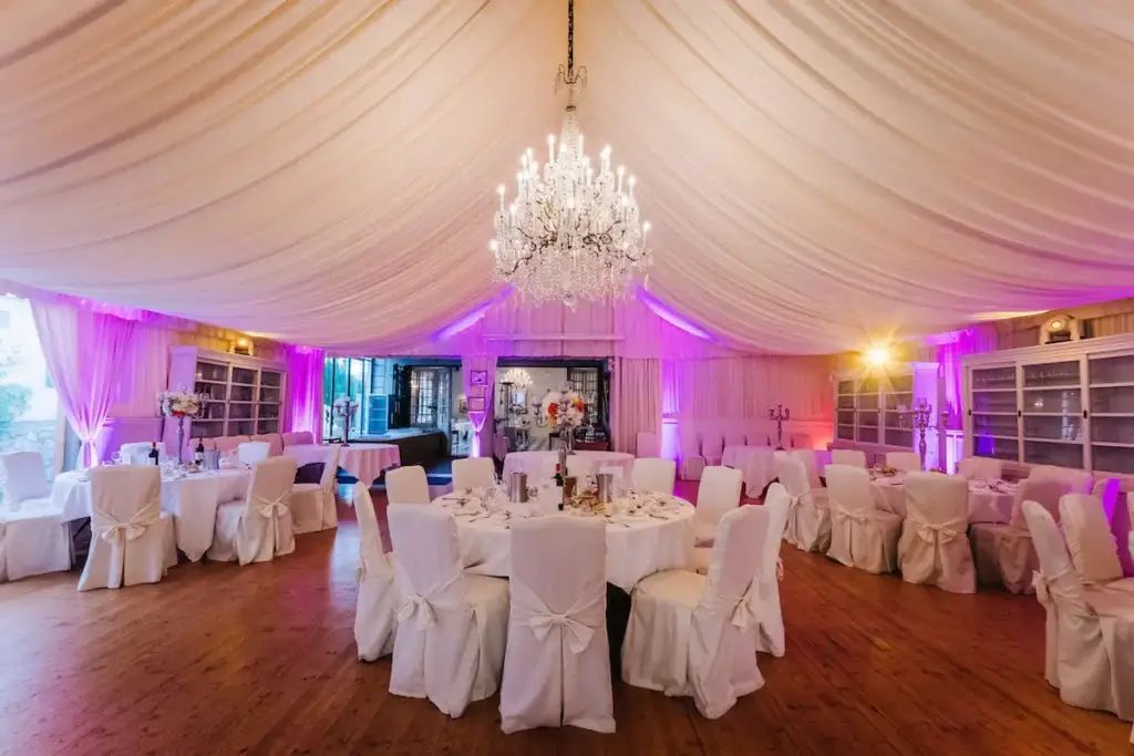 Salle de réception des Pins Penchés avec tables rondes, plafond drapé et lustre