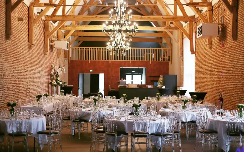 Salle de réception du Clos du Colombier avec tables dressées et poutres apparentes