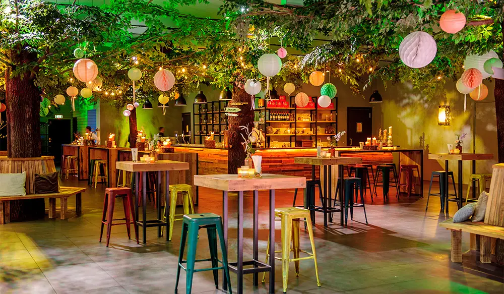 Feestopstelling met hoge tafels en kleurrijke verlichting in ’t Buitenhuys