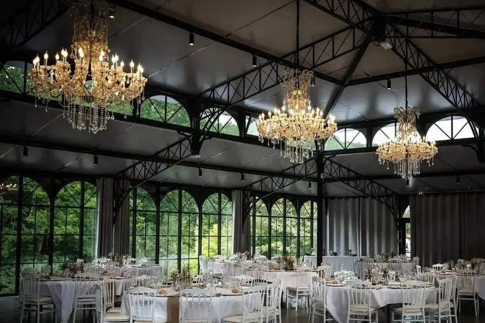 Intérieur de la verrière de l'Orangerie de Kerstrad avec tables et lustres