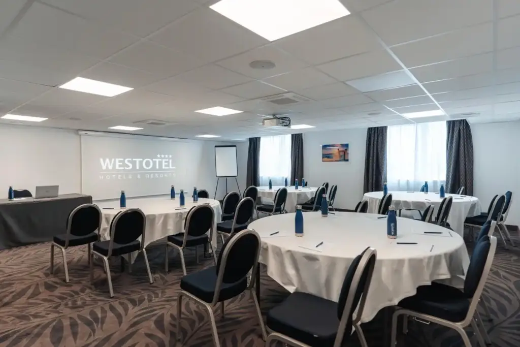 Meeting room at Westotel Taverny with tables, chairs and a presentation screen